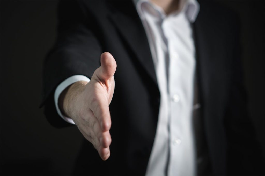 close-up-of-human-hand-327540 Close-up of a businessman extending hand for a handshake, symbolizing agreement and partnership.