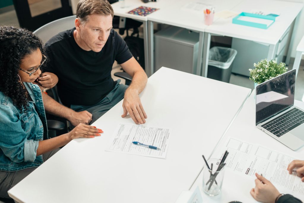 pexels-photo-7979404-7979404 A couple discusses legal documents with a professional in a modern office setting.